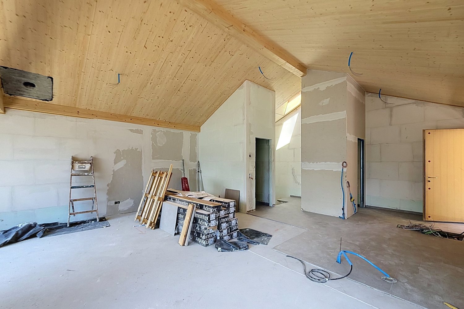 Étage brut avec plafond en bois massif et cloisons non finies.